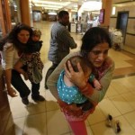 Women carrying children run for safety as armed police hunt gunmen who went on a shooting spree in Westgate shopping centre in Nairobi